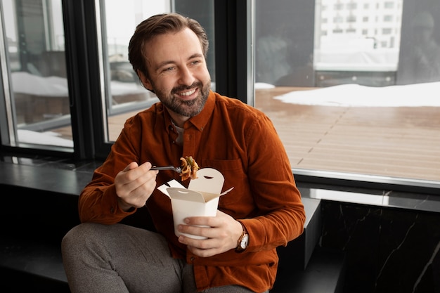 Medium shot smiley man eating noodles