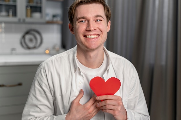 Medium shot smiley man holding heart shape