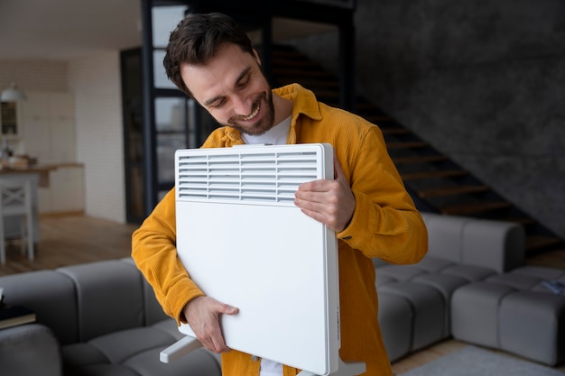 Free photo medium shot smiley man holding heater