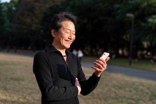 Uomo sorridente con colpo medio che tiene il telefono