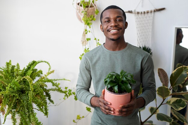 Medium shot smiley man holding plant at home