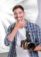 Foto gratuita uomo di smiley del colpo medio che tiene una macchina fotografica professionale