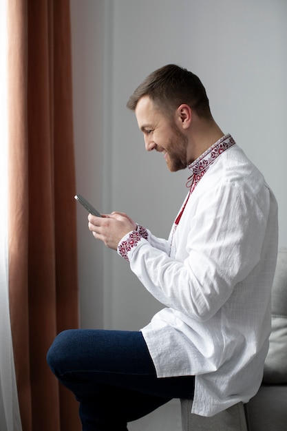 Uomo sorridente del colpo medio che tiene smartphone