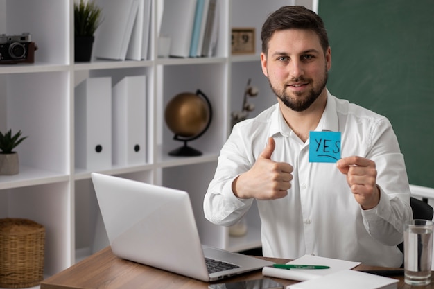 Medium shot smiley man making list with laptop