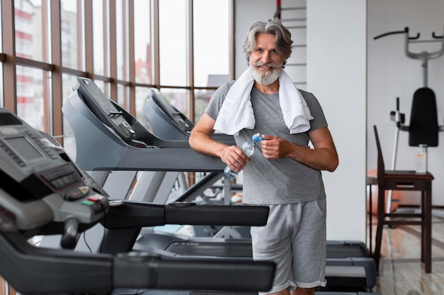 Medium shot smiley man posing at gym