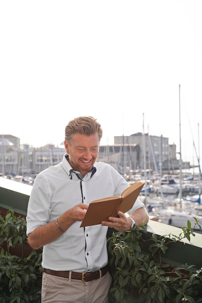 Libro di lettura dell'uomo sorridente a colpo medio