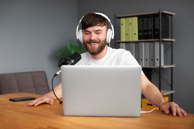 실내에서 팟캐스트를 녹음하는 중간 샷 웃는 남자