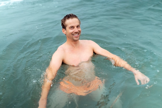 Foto gratuita uomo sorridente a tiro medio in riva al mare