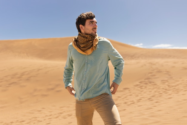 Medium shot smiley man wearing scarf in desert