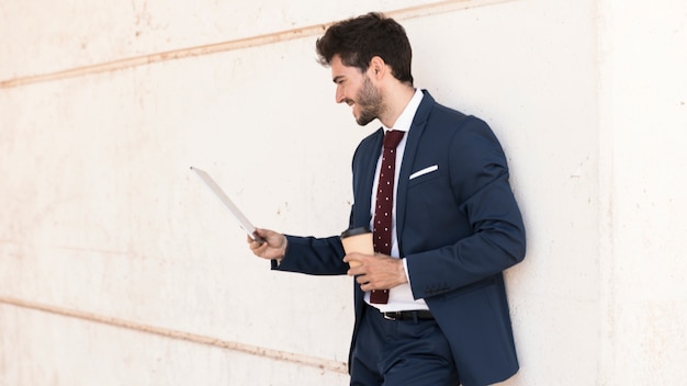 Uomo di smiley di tiro medio con caffè e tablet