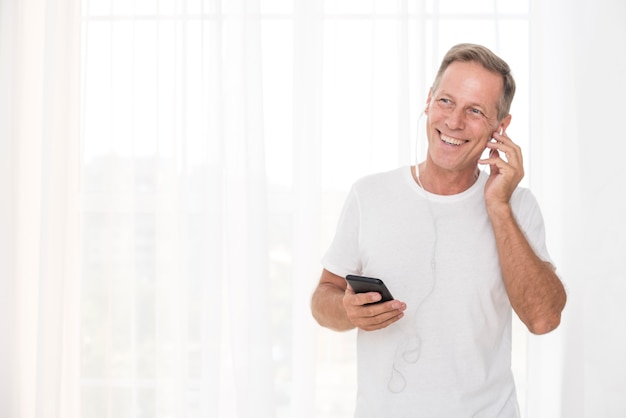 Medium shot smiley man with smartphone and headphones