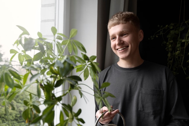 Foto gratuita uomo sorridente del colpo medio con l'annaffiatoio