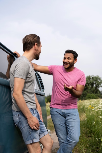 Free photo medium shot smiley men chatting near van