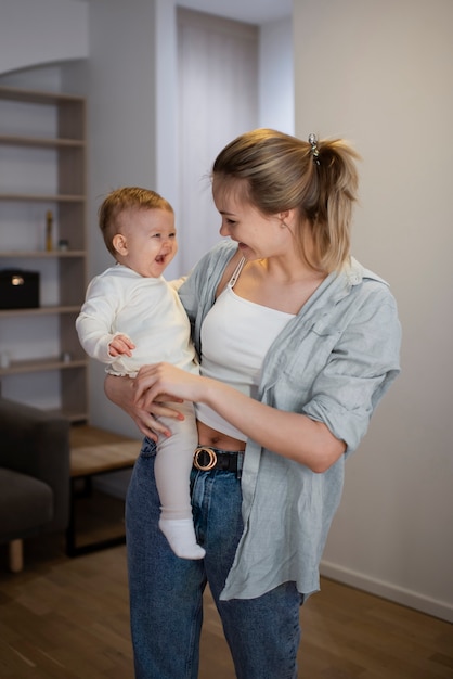 Free photo medium shot smiley mother holding baby