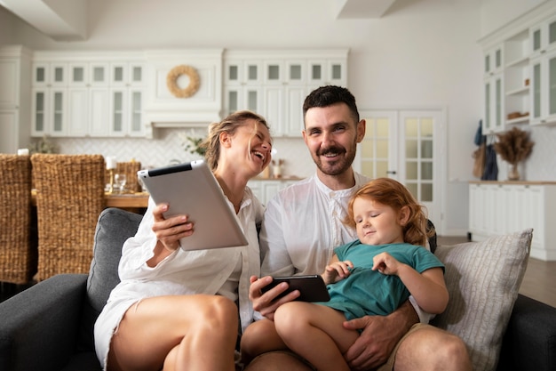 Medium shot smiley parents and kid with devices