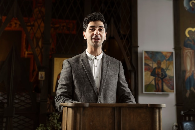 Free photo medium shot smiley pastor preaching at church