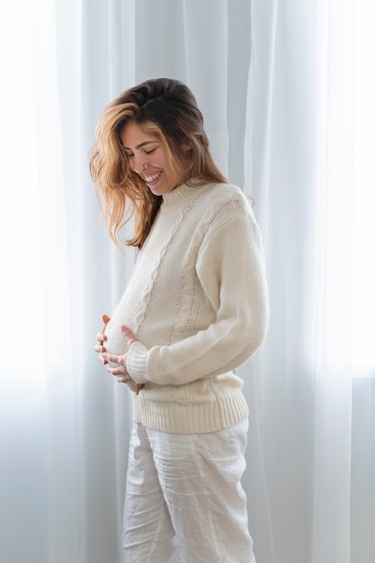 Medium shot smiley pregnant woman at home