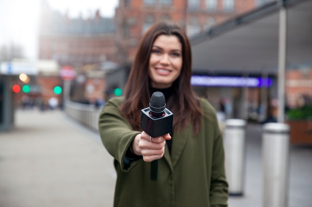 Medium shot smiley reporter holding microphone