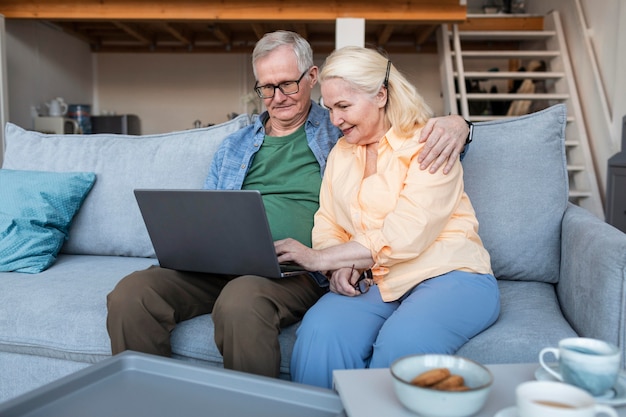 Medium shot smiley retired couple with laptop