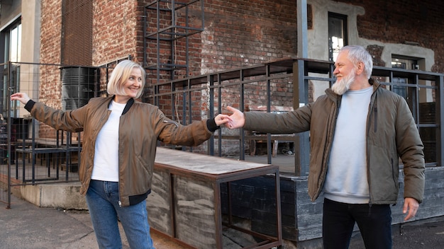 Free photo medium shot smiley senior couple dancing outdoors