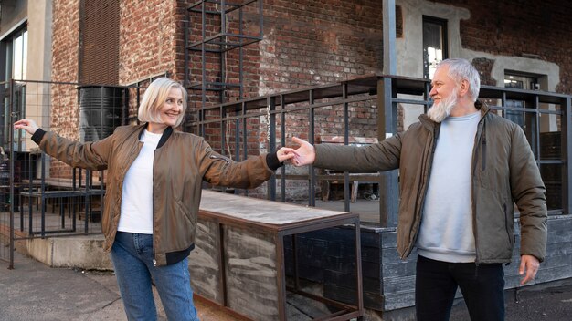 Medium shot smiley senior couple dancing outdoors