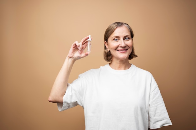 Free photo medium shot smiley senior woman holding serum