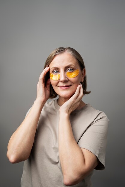 Medium shot smiley senior woman using eye patches