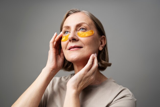 Medium shot smiley senior woman using eye patches