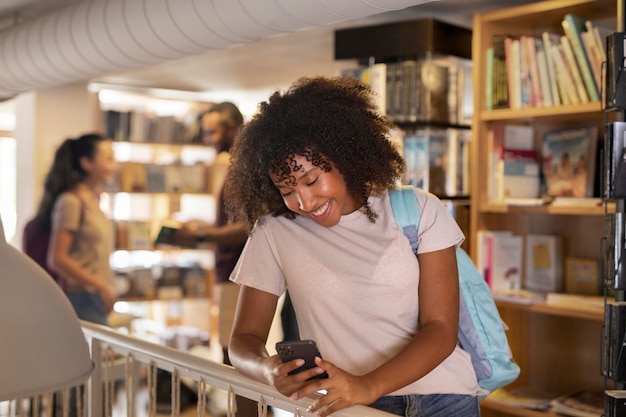 Medium shot smiley student holding smartphone