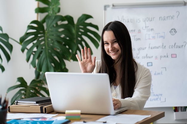 Insegnante di smiley di tiro medio con il computer portatile