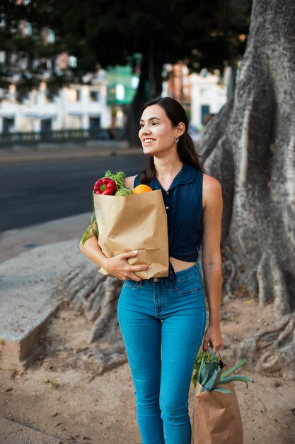 紙袋を運ぶミディアムショットの笑顔の女性