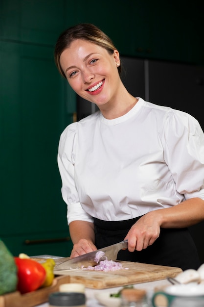 Foto gratuita cipolla di taglio della donna di smiley del colpo medio