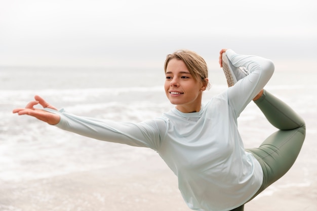 Foto gratuita donna sorridente del colpo medio che fa yoga