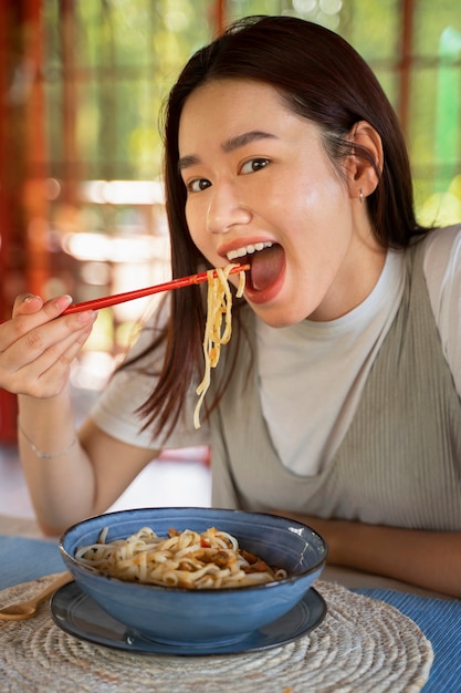 免费照片中景镜头笑脸女人吃面条