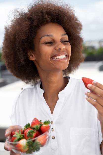 Medium shot smiley woman eating strawberries