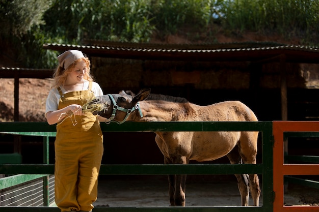 Foto gratuita donna sorridente a colpo medio che allatta il cavallo