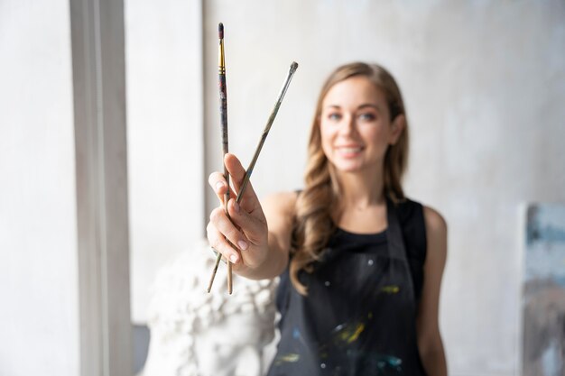 Medium shot smiley woman holding brushes