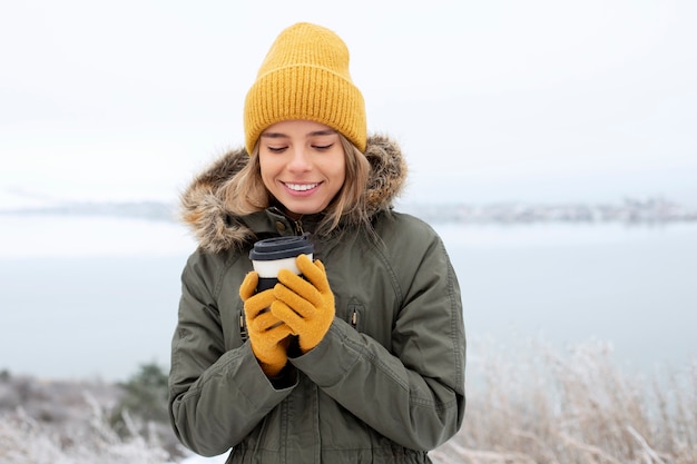 カップを保持しているミディアムショットのスマイリー女性