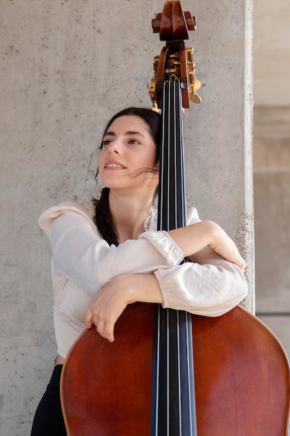 Free photo medium shot smiley woman holding double bass