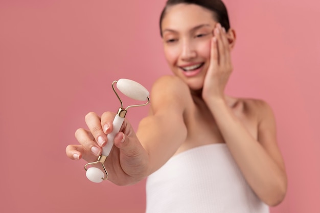 Foto gratuita rullo per il viso della holding della donna di smiley del colpo medio