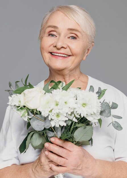 Medium shot smiley woman holding flowers