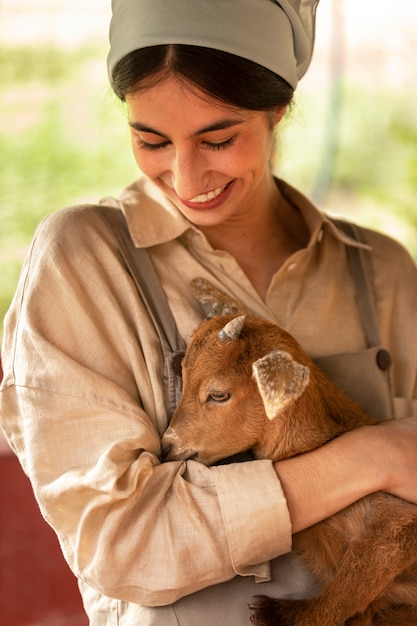 Free photo medium shot smiley woman holding little goat