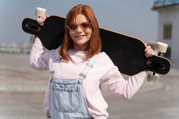 Longboard를 들고 중간 샷 웃는 여자