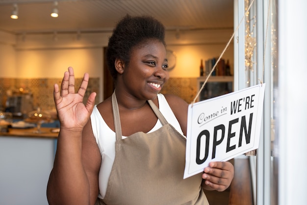 Medium shot smiley woman holding open sign