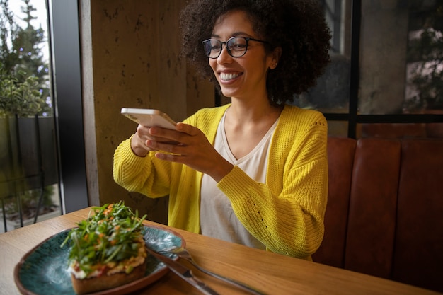 Foto gratuita donna sorridente con colpo medio che tiene il telefono