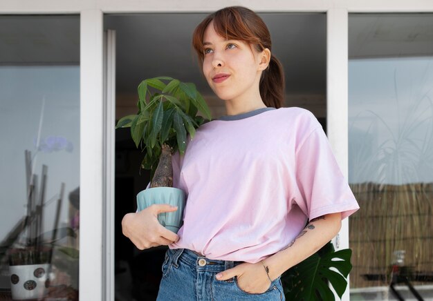 Medium shot smiley woman holding plant pot