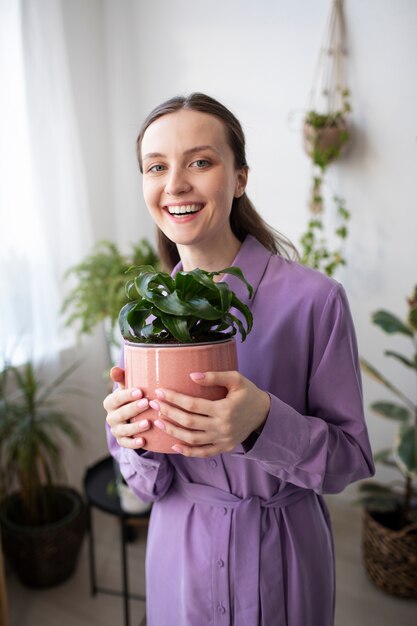 Medium shot smiley woman holding plant