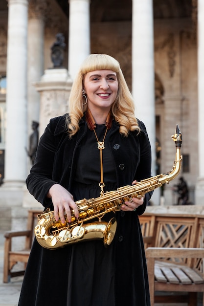 Medium shot smiley woman holding saxophone