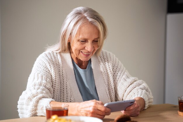 Foto gratuita donna sorridente del colpo medio che tiene smartphone