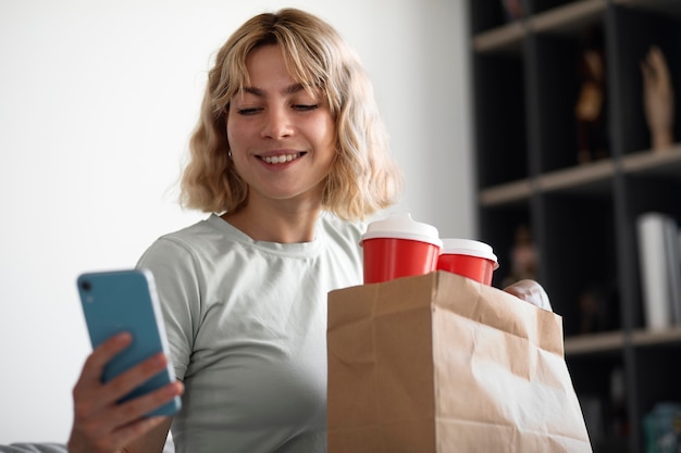 Free photo medium shot smiley woman holding smartphone